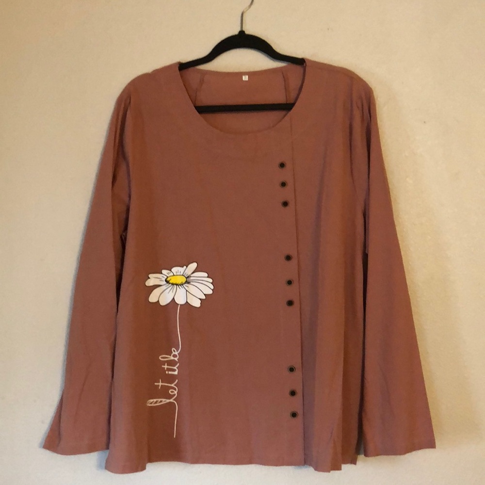A blouse with a daisy on it that says “let it be”.